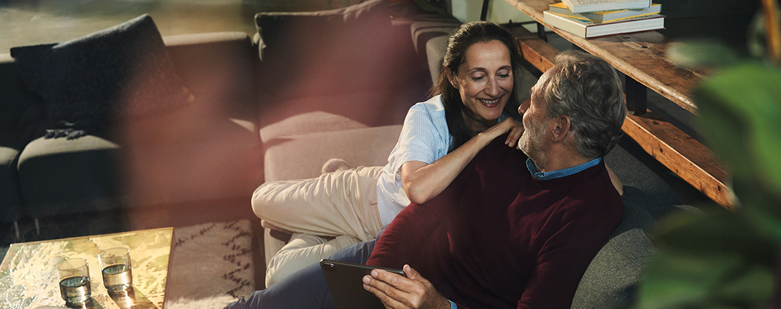 Älteres Paar liegt entspannt mit Tablet auf der Couch